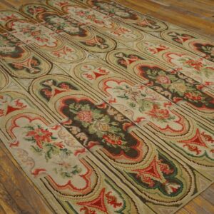 Low-pile rug with alternating dark floral panels and light stylized arches rests on rustic wood flooring.