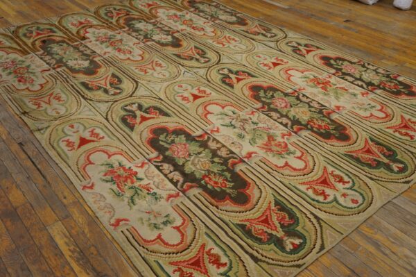 Low-pile rug with alternating dark floral panels and light stylized arches rests on rustic wood flooring.