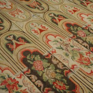 A flatwoven rug displays a repeating trellis pattern of floral bouquets set in dark brown and light beige frames.