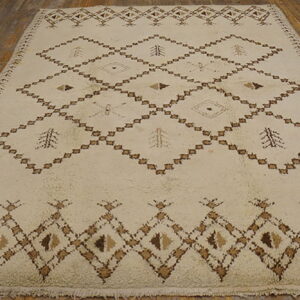 A cream shaggy rug with brown geometric diamond and tree patterns lies on a rustic wood floor.