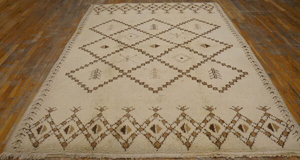 A cream shaggy rug with brown geometric diamond and tree patterns lies on a rustic wood floor.