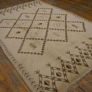 Off-white high-pile rug with dark brown geometric diamond patterns rests on rustic wood plank flooring.