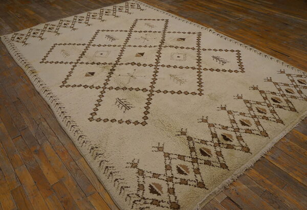 Off-white high-pile rug with dark brown geometric diamond patterns rests on rustic wood plank flooring.