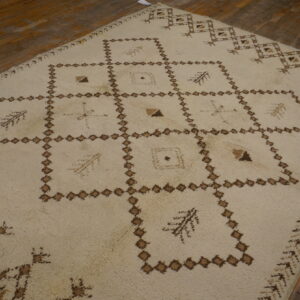 High-pile ivory rug featuring a brown grid of diamonds and abstract symbols rests on warm wood flooring.