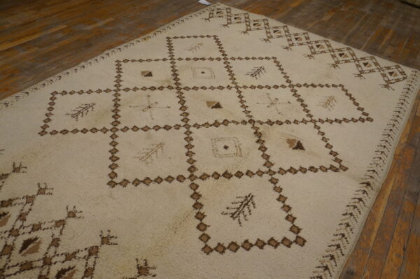 High-pile ivory rug featuring a brown grid of diamonds and abstract symbols rests on warm wood flooring.