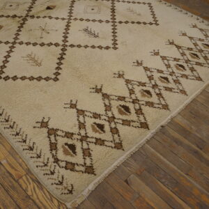 High-pile cream rug with dark brown geometric and abstract patterns shown on rustic wood planks.