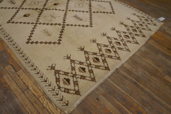 High-pile cream rug with dark brown geometric and abstract patterns shown on rustic wood planks.