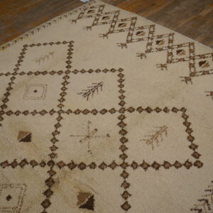 Shaggy ivory rug with a large brown geometric pattern covering a distressed wood plank floor.