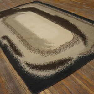 A shaggy rug with an abstract brown and beige swirling pattern rests on rustic plank flooring.