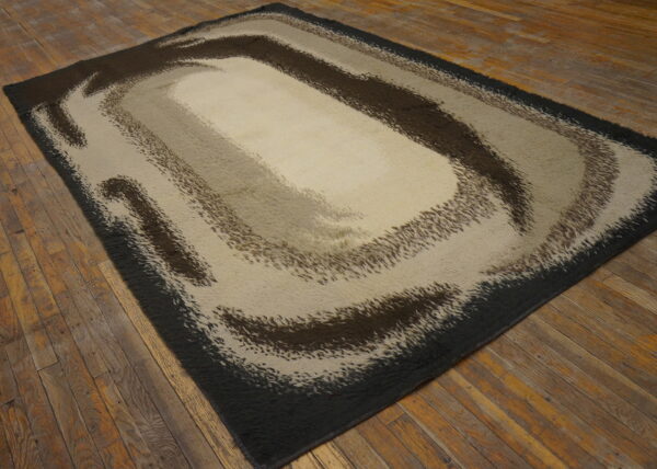 A shaggy rug with an abstract brown and beige swirling pattern rests on rustic plank flooring.
