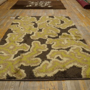 Shaggy brown, beige, and lime green abstract rug displayed on wide plank wood floors.