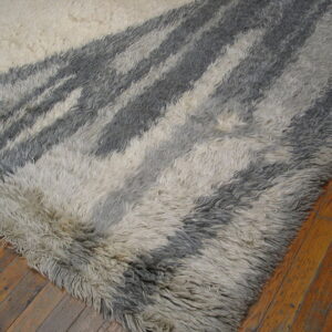 High-pile rug with abstract white and charcoal gray stripes resting on rustic wood planks.