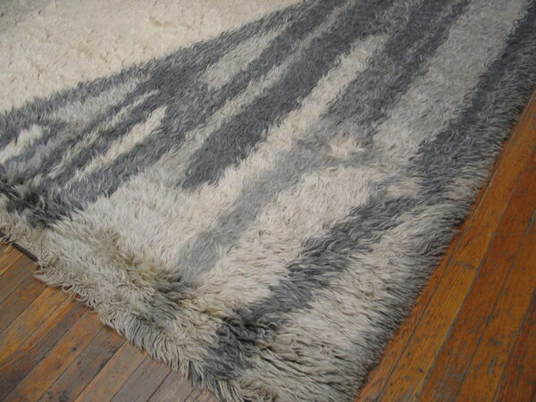 High-pile rug with abstract white and charcoal gray stripes resting on rustic wood planks.
