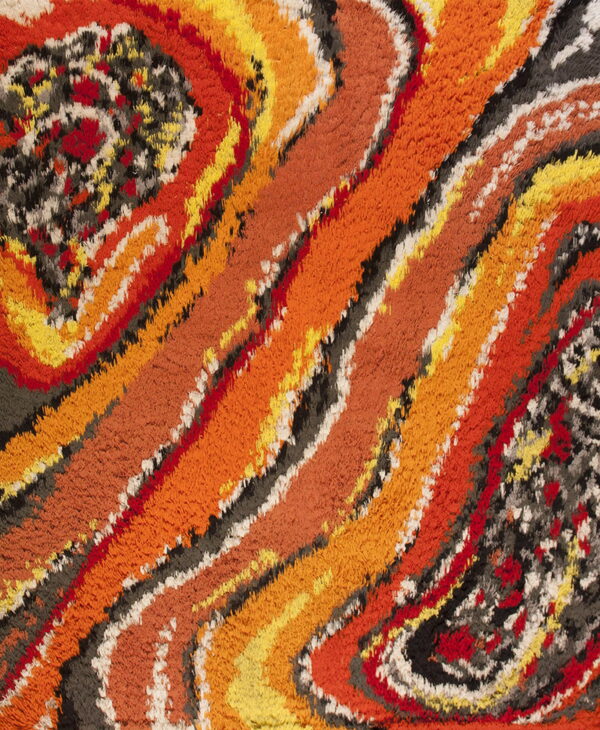 Textured high-pile rug detail showing swirling bands of orange, yellow, red, gray, and black.
