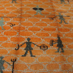 Burnt orange high-pile rug displays a gray trellis pattern and scattered abstract figures on hardwood flooring.