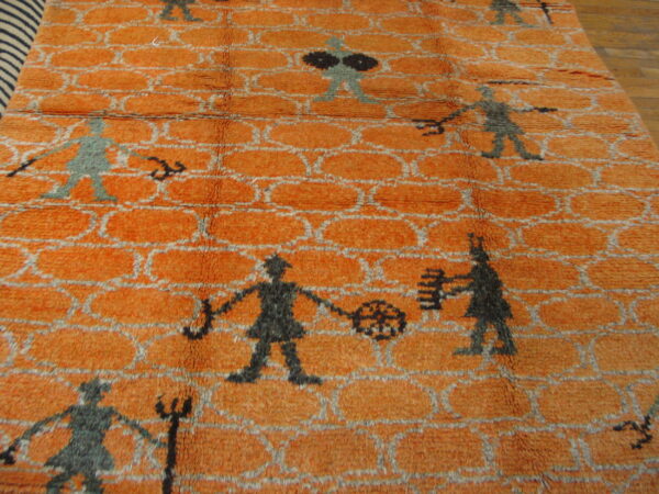 Burnt orange high-pile rug displays a gray trellis pattern and scattered abstract figures on hardwood flooring.