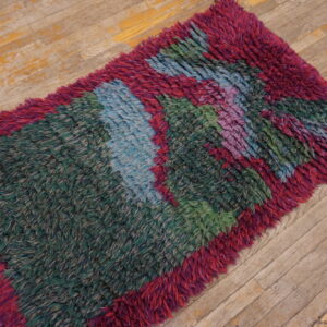 High-pile, shaggy rug runner featuring bold stripes of green, magenta, blue, and purple on worn wood planks.