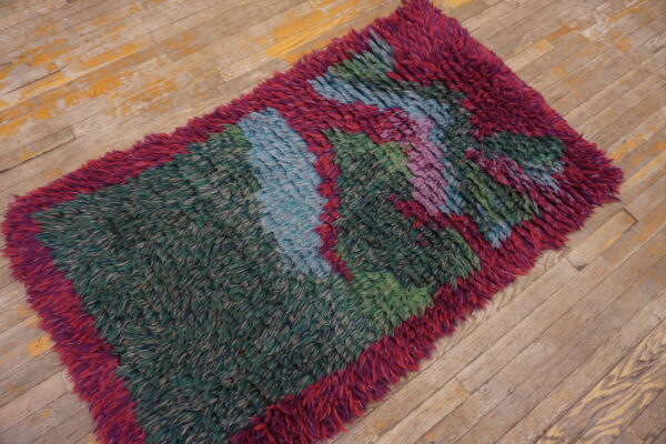 High-pile, shaggy rug runner featuring bold stripes of green, magenta, blue, and purple on worn wood planks.