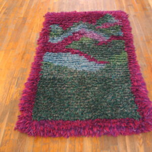 High-pile shag rug in abstract green, blue, and pink patterns framed by a magenta border on wood flooring.