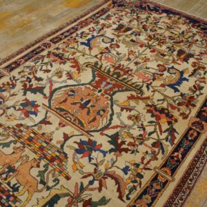 Traditional cream rug with colorful dense floral and fauna patterns resting on distressed wooden flooring.