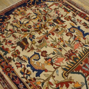 Traditional rug with a multicolored floral design on a cream field and dark blue border, placed on wood floors.