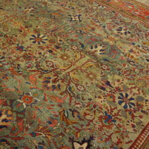 Low-pile rug with a dense green, red, and blue floral pattern visible on wooden flooring.