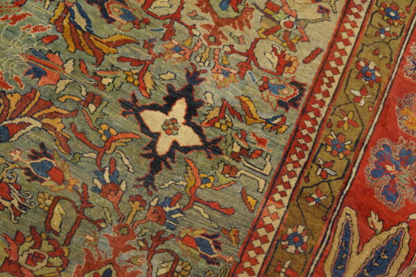 Close-up of a low-pile rug with a teal field, complex red and blue floral patterns, and multi-banded border.