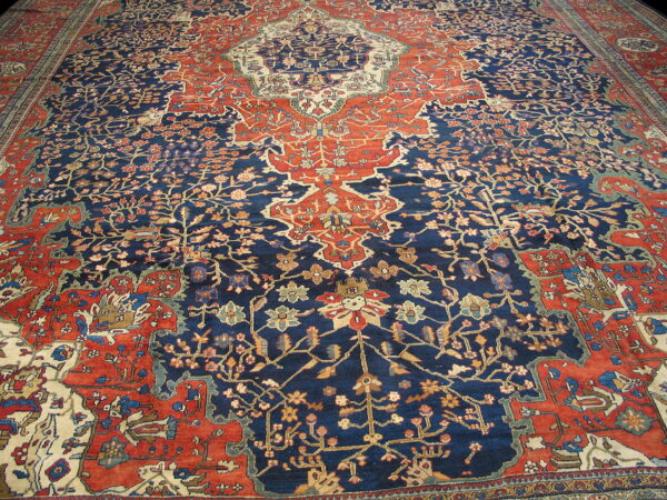 Traditional high-pile rug featuring a central medallion and intricate patterns in navy blue, brick red, and cream.