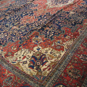 Low-pile rug featuring complex floral designs in contrasting navy blue, rust red, and cream.