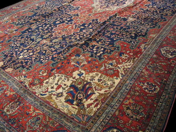 Low-pile rug featuring complex floral designs in contrasting navy blue, rust red, and cream.