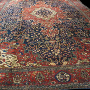 Traditional area rug featuring a navy blue field, rust red border, and complex cream and red motifs.