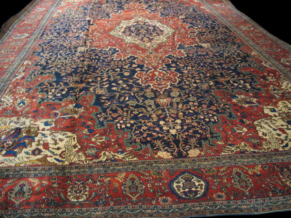 Traditional area rug featuring a navy blue field, rust red border, and complex cream and red motifs.