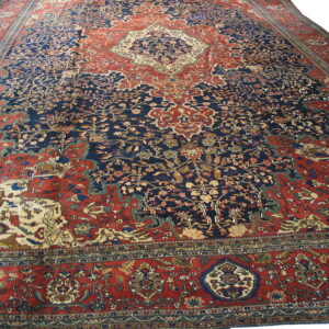 Large traditional rug featuring a dense floral pattern in navy blue, rust red, and cream.