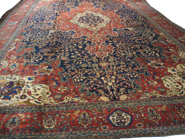 Large traditional rug featuring a dense floral pattern in navy blue, rust red, and cream.