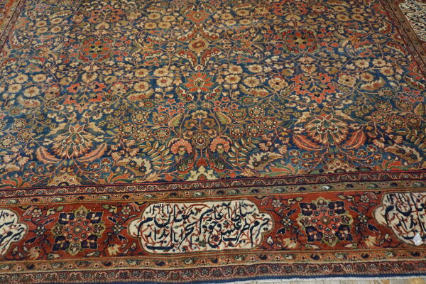 A detailed blue rug featuring an all-over floral pattern, wide rust border, and calligraphic cartouches.