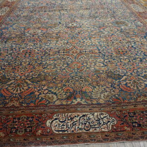 A densely patterned blue and rust floral rug with script borders rests on weathered wood floors.