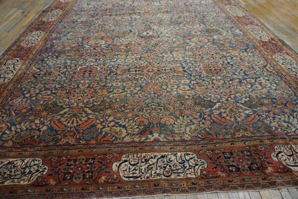 A densely patterned blue and rust floral rug with script borders rests on weathered wood floors.