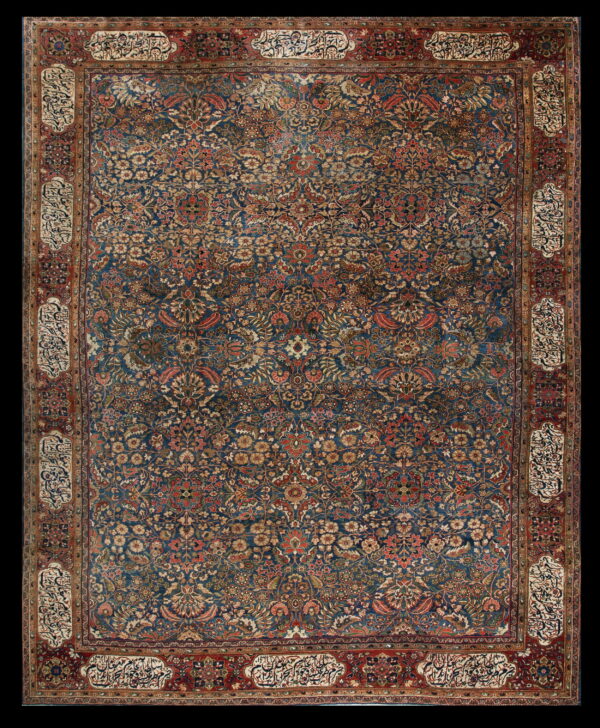 Intricate blue rug with dense red and gold floral motifs and an elaborate border containing calligraphic panels.