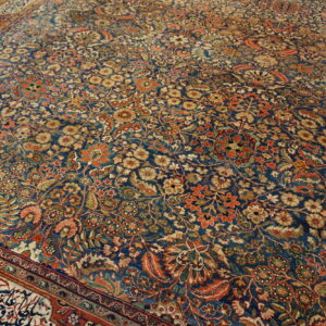 Intricate floral patterned rug with a blue field, featuring rust, gold, and cream flowers and a detailed red border.