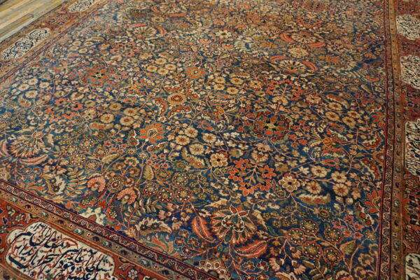 Intricate floral patterned rug with a blue field, featuring rust, gold, and cream flowers and a detailed red border.