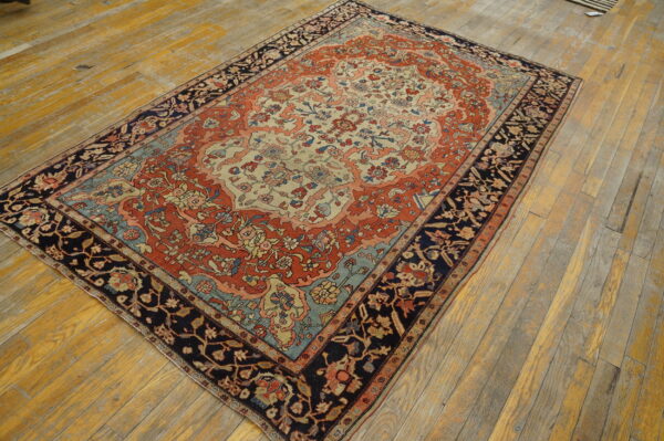 Terracotta, ivory, and navy traditional rug with a floral medallion pattern resting on distressed wood planks.