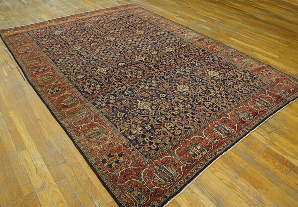 Traditional navy blue and rust area rug with an all-over intricate pattern on light wood floors.