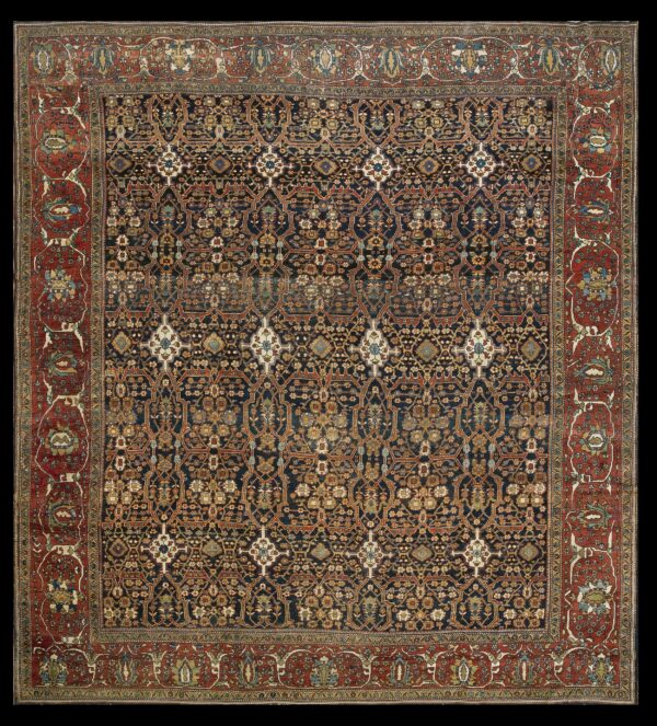 Square rug with a navy and gold floral trellis field and a wide rust-red border featuring stylized palmettes.