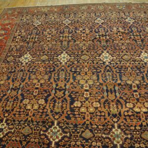 Low-pile rug with a detailed dark blue trellis pattern and wide rust border on plank wood flooring.