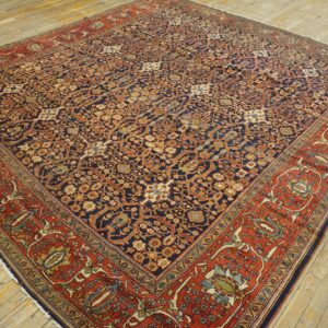 Ornate navy and rust rug featuring intricate floral designs sits centered on light wood plank flooring.