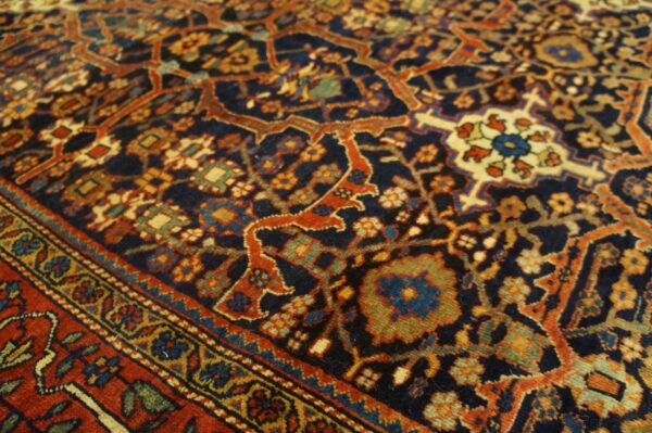 Ornate traditional rug with a navy field, detailed floral patterns, and a contrasting border in rust and gold.