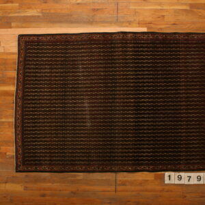 Dark rectangular rug featuring dense horizontal geometric rows and a patterned border on natural wood flooring.