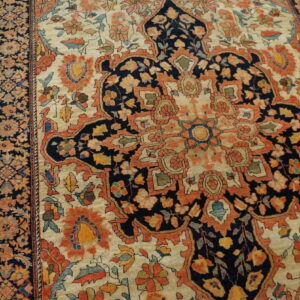 Floral patterned rug in navy, rust, and cream colors, centered on distressed yellow wood planks.