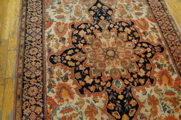 Floral patterned rug in navy, rust, and cream colors, centered on distressed yellow wood planks.