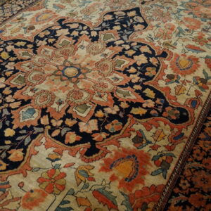 Ornate traditional rug in navy, terracotta, and cream with a detailed floral design on hardwood floors.